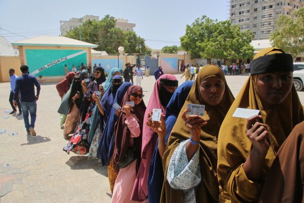 Women queue at a polling station in the capital, holding up their identification cards as they wait to vote.